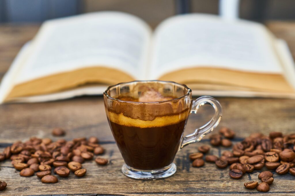 illustration d'une tasse de café à côté de grain de café avec un livre en arrière plan