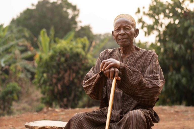 Photo d'un vieille homme éthiopien assis avec les mains qui reposent sur une canne